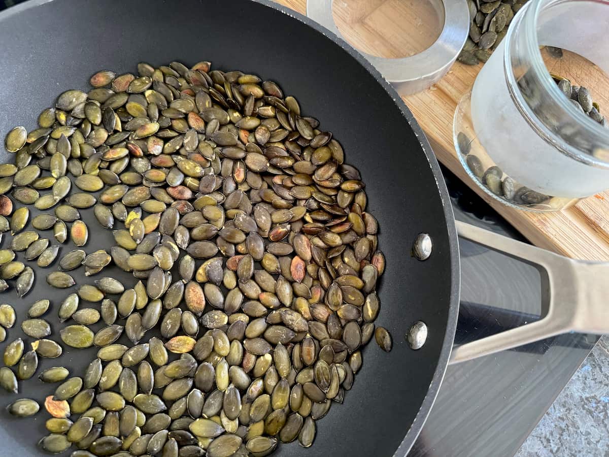 toasting green pumpkin seeds in a non-stick frying pan