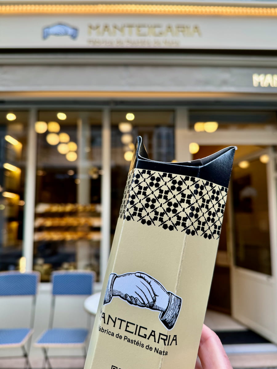 holding a special custard tart box in front of one of the best pasteis de nata shops in Paris
