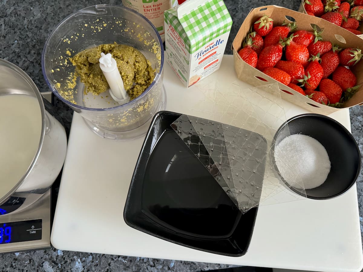 ingredients laid out for a pistachio panna cotta - cream, milk, sugar, gelatin sheets and pistachio paste