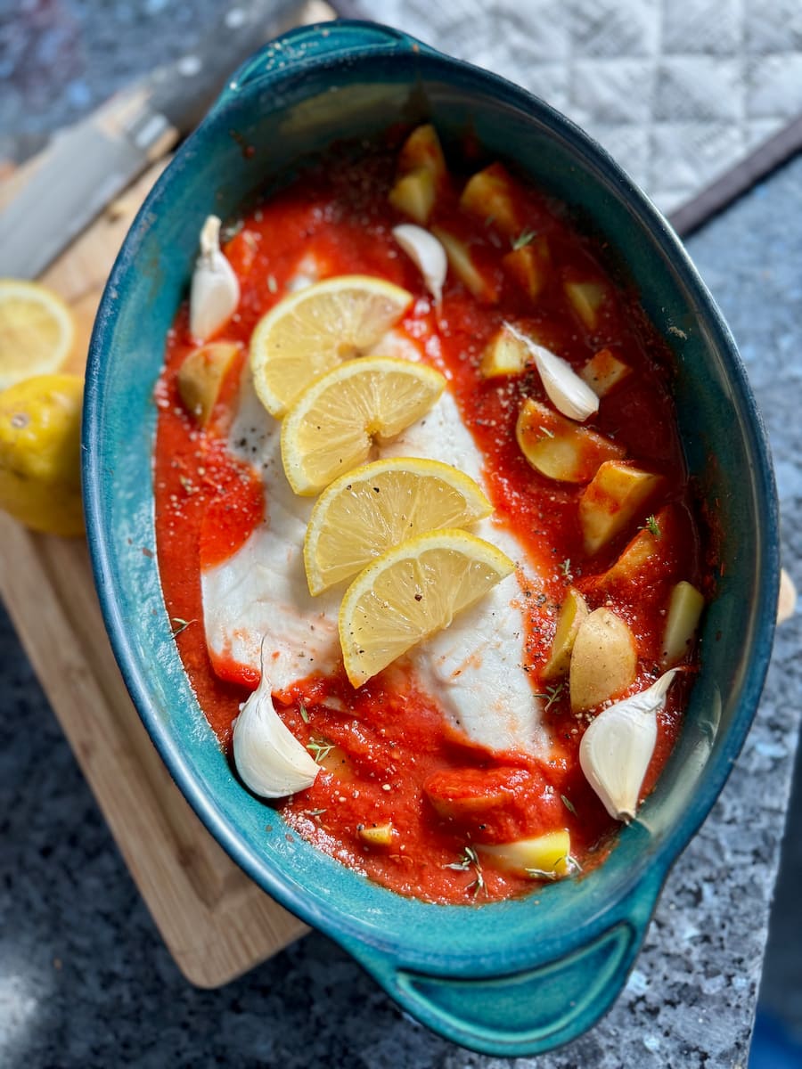 sea bream fish baked in tomato sauce with potatoes, garlic, herbs and lemon