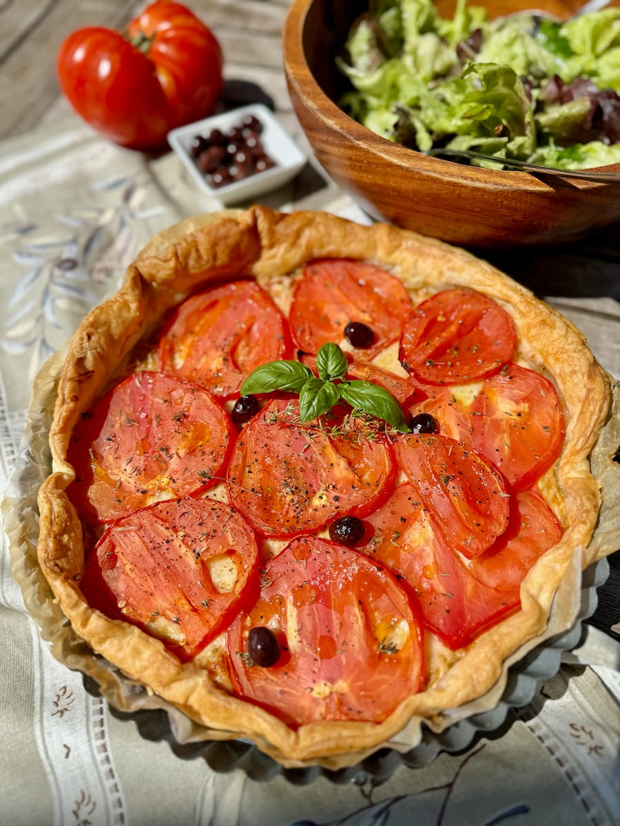 baked French tomato tart with cheese, mustard and olives served with a green salad