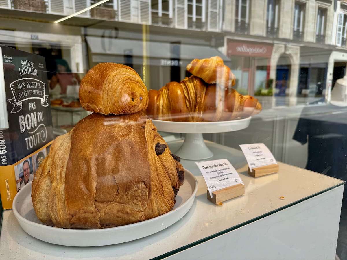 giant pain au chocolat and croissants in the window of a Paris bakery
