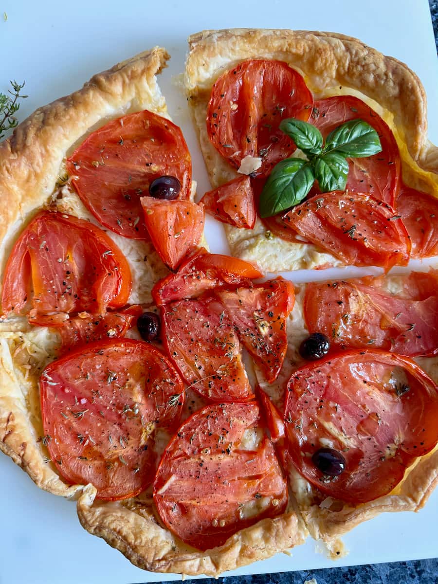 sliced tomato tart with visible layer of white Emmental cheese underneath the tomato slices