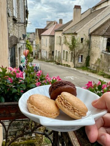 holding a scalloped plate of French macarons in the town of Vezelay in France