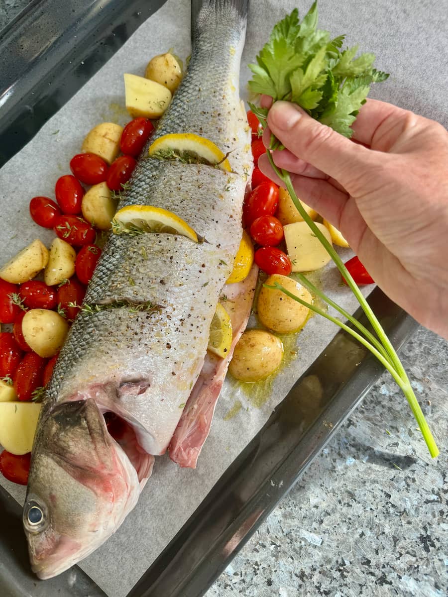 removing parsley leaves from the stalks before stuffing a whole sea bass fish