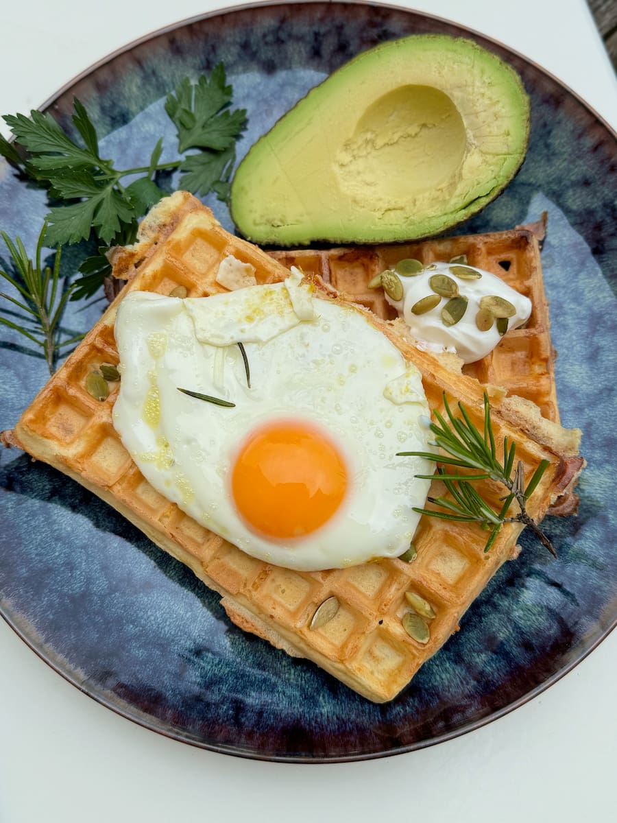 savoury waffles topped with a fried egg sunny side up with half an avocado