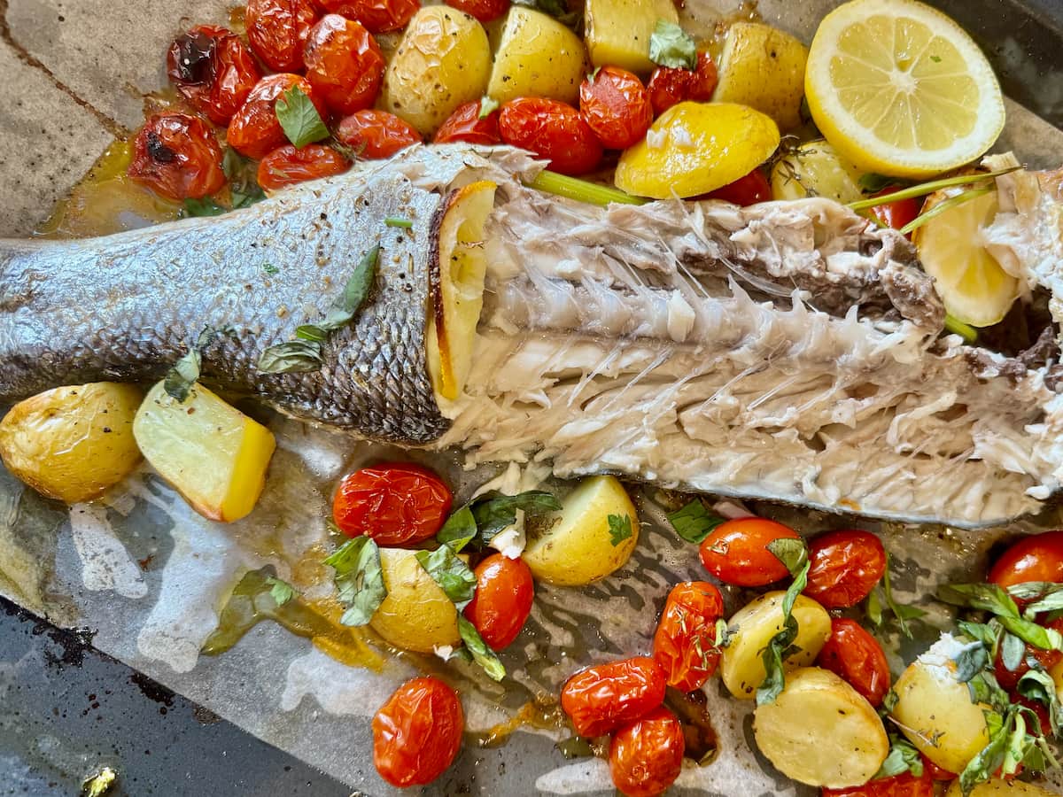 whole baked sea bass cut through the middle to the bone, showing its delicate fish meat