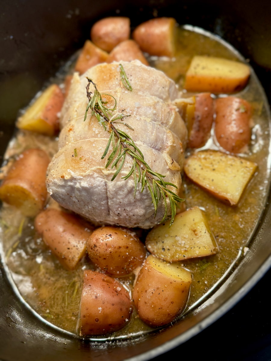 cooking a pork roast in a crock pot with potatoes and rosemary herbs
