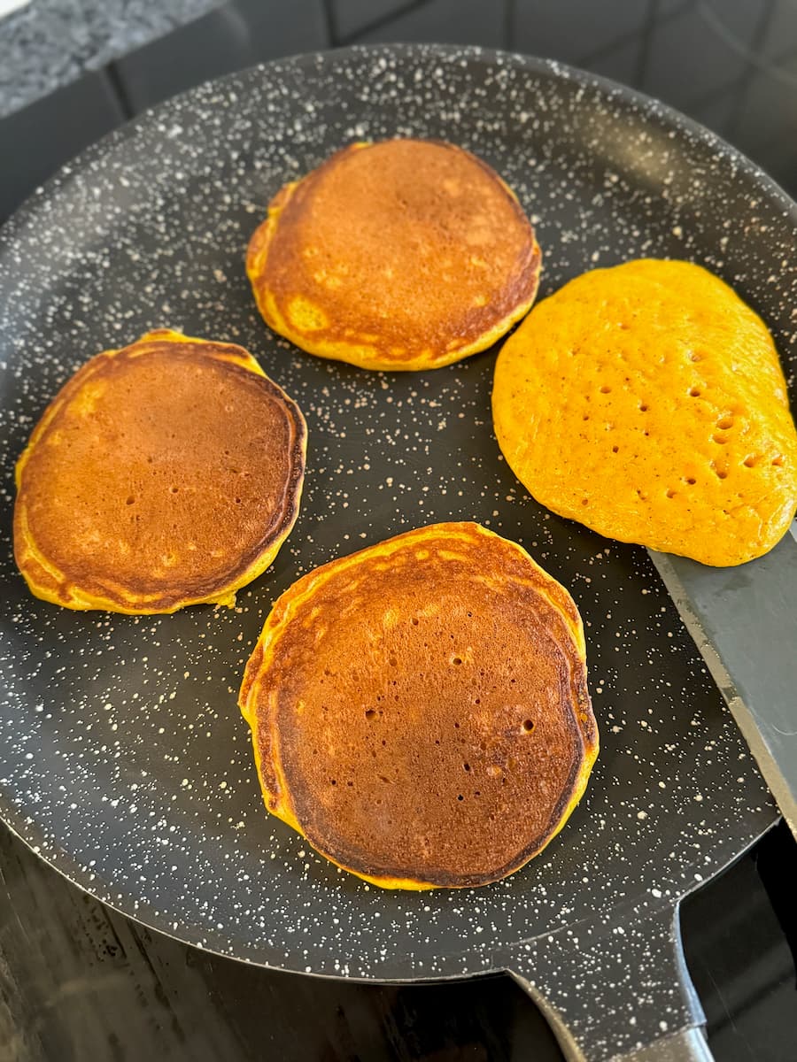 small pumpkin pancakes made with cottage cheese cooking in a pan