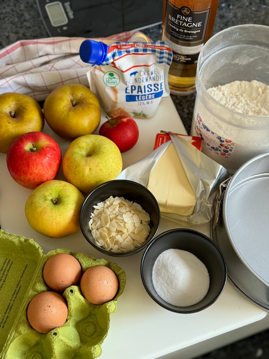 French ingredients for apple cake: apples, eggs, sugar, butter, flour, creme fraiche, almonds and Calvados liqueur