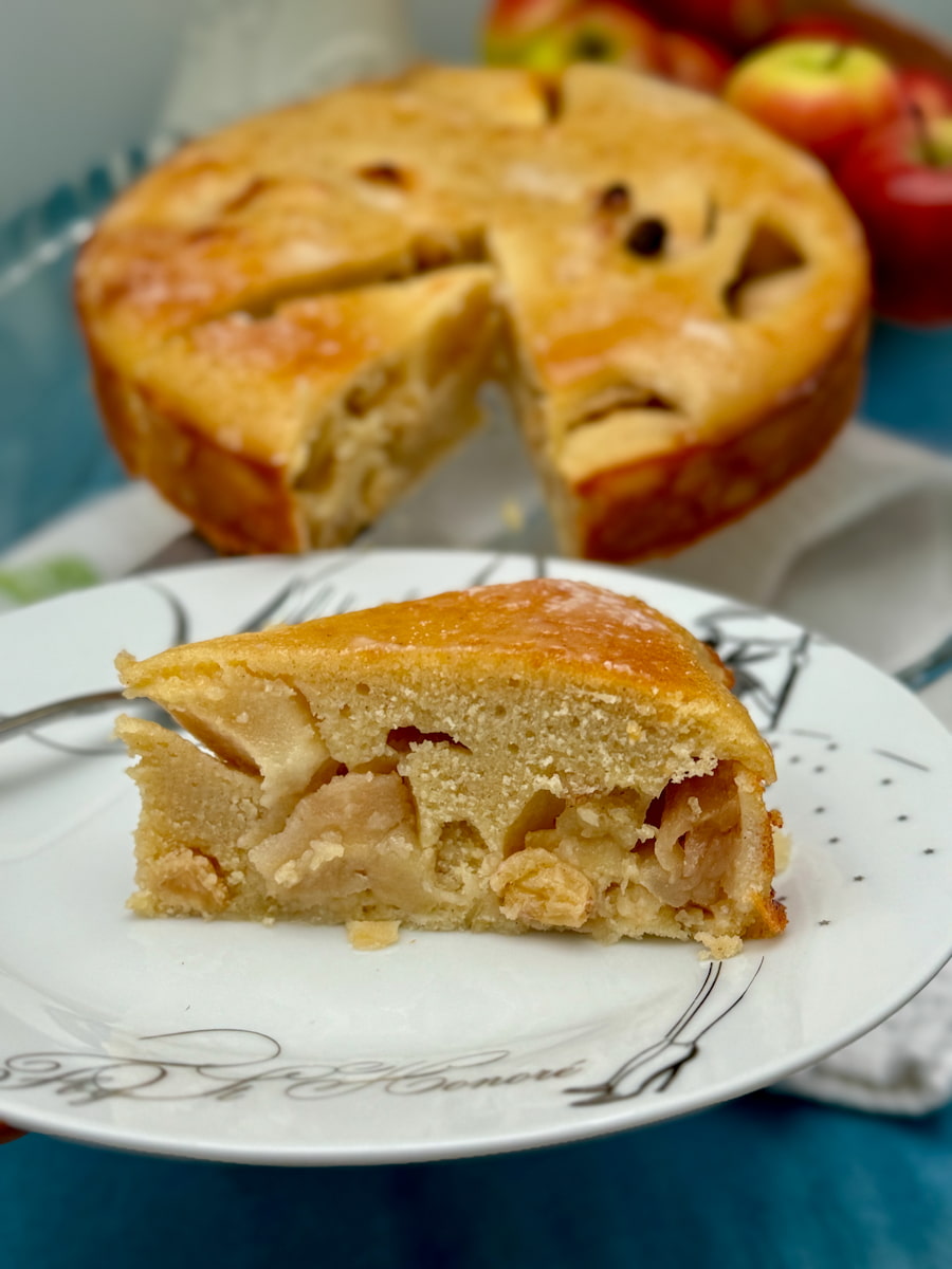 slice from a round apple cake, extra moist with lots of baked apples and raisins