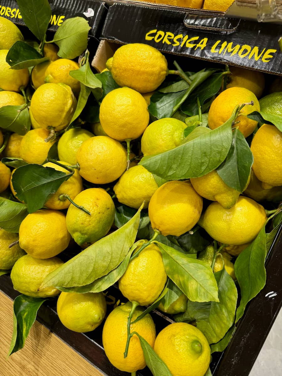 Lemons from Corsica in a box with leaf branches at the French market