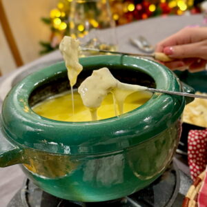 dipping skewers of bread and cauliflower into a pot of cheese fondue
