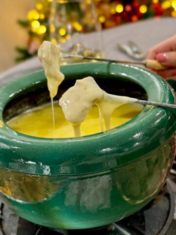 dipping skewers of bread and cauliflower into a pot of cheese fondue
