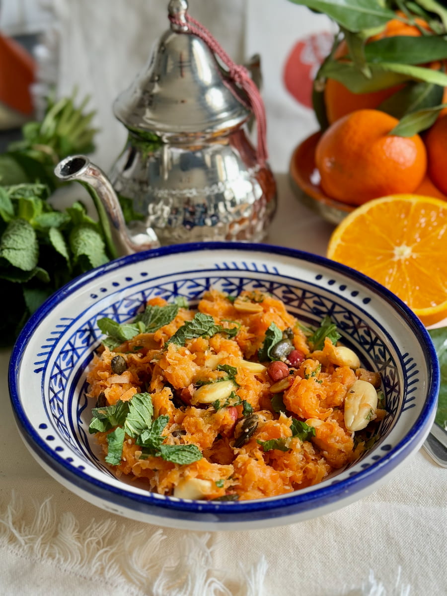 Moroccan handpainted dish with a salad of shredded raw carrots, radish, spices, mint and orange.