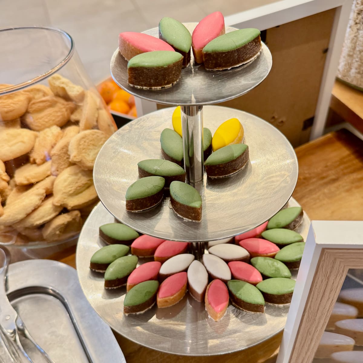 cake stand with diamond shaped almond confections in green, white, yellow and pink