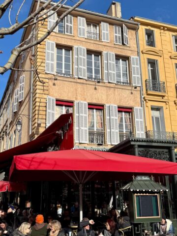 bustling café in Aix-en-Provence in the sunshine with people drinking coffee outside next to a plane tree