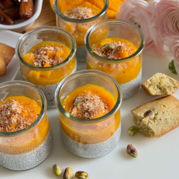 glass pots with coconut chia pudding topped with mango sauce, mango chunks and dates