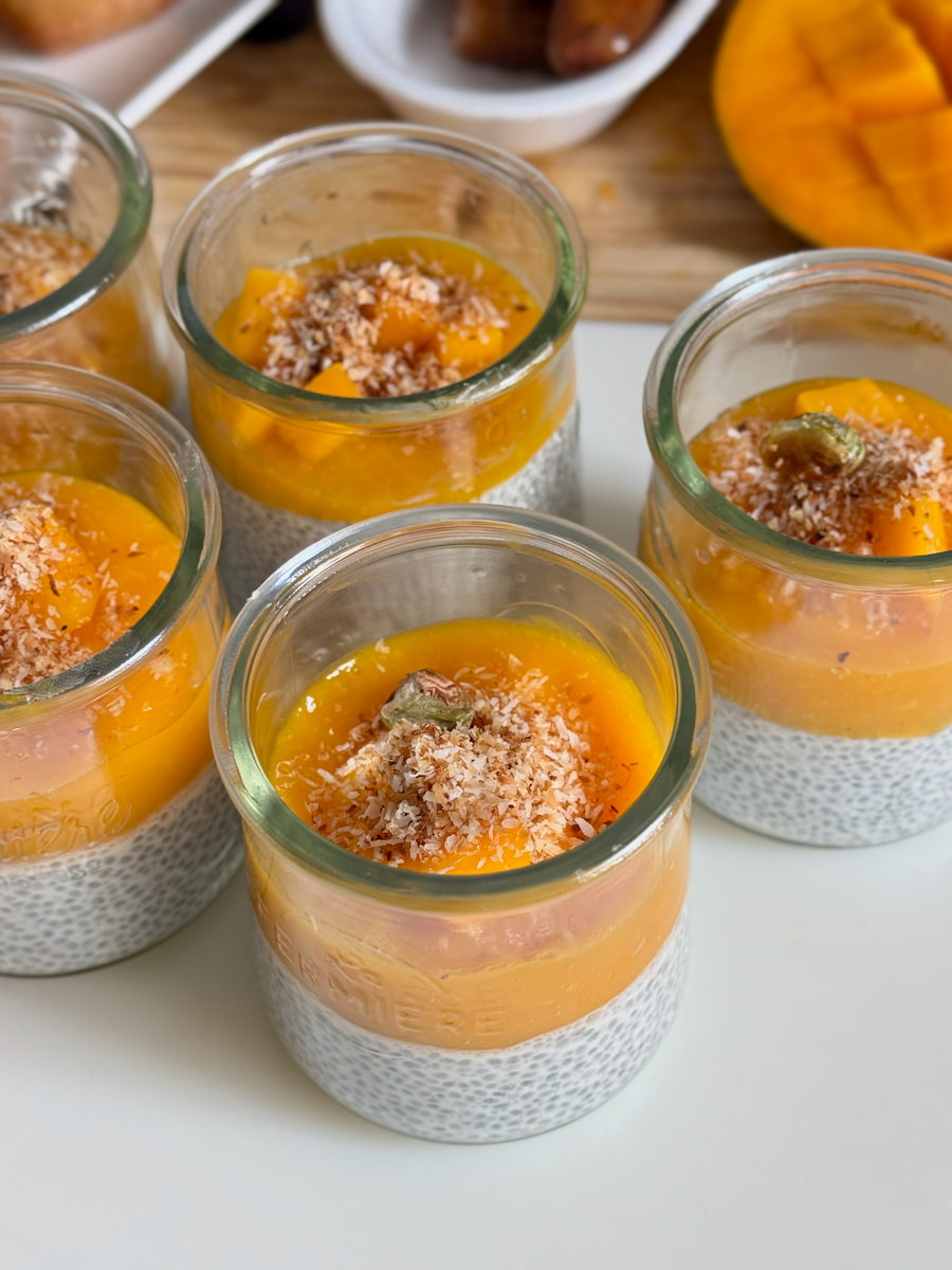 glass yoghurt pots filled with chia pudding made with coconut milk and topped with mango sauce
