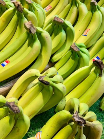bunches of fresh green bananas with French flag stickers