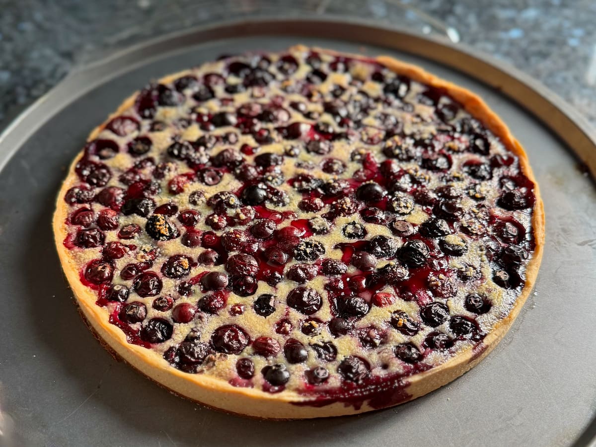 blueberry tart just out of the oven with burst baked blueberries on a baking tray