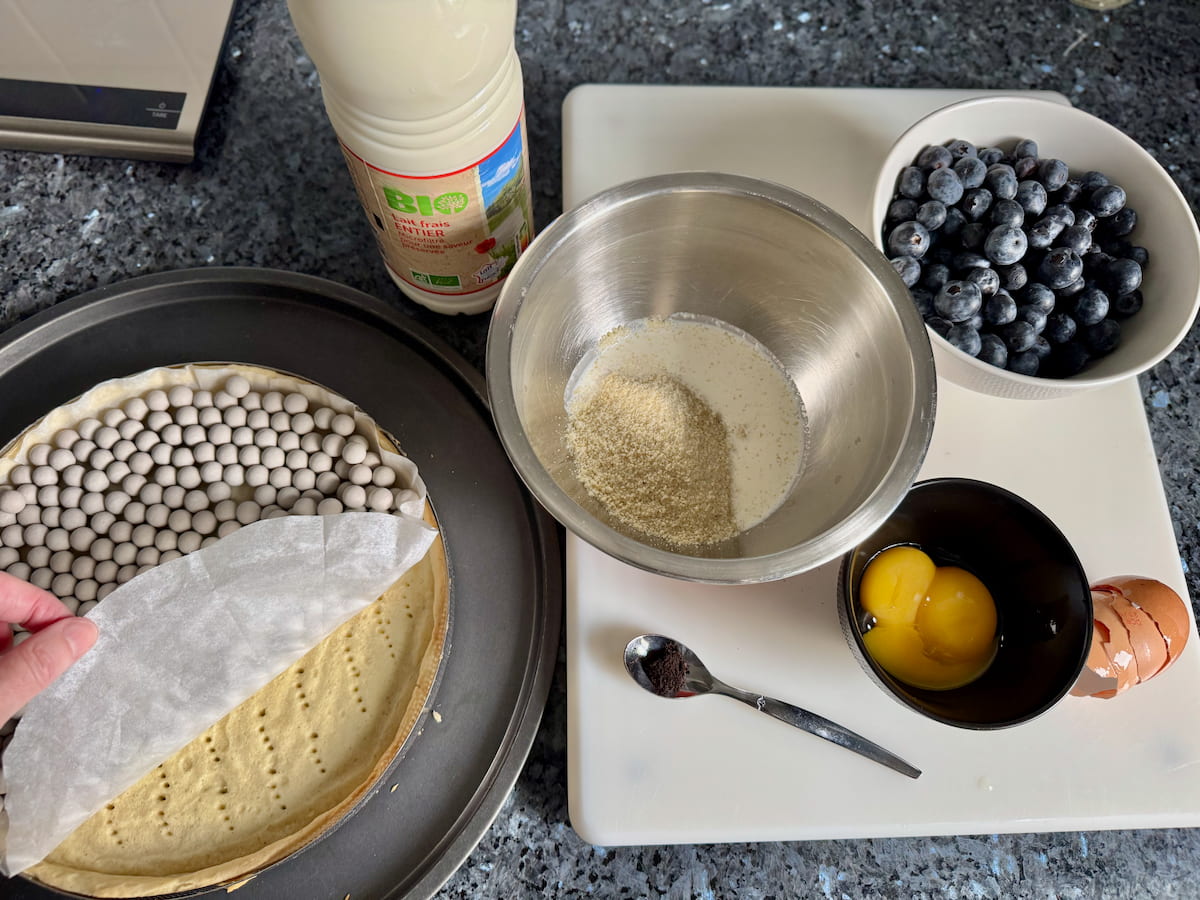 ingredients for a blueberry tart: sweet pastry, 2 egg yolks, blueberries, almond flour, sugar, vanilla, milk and cream
