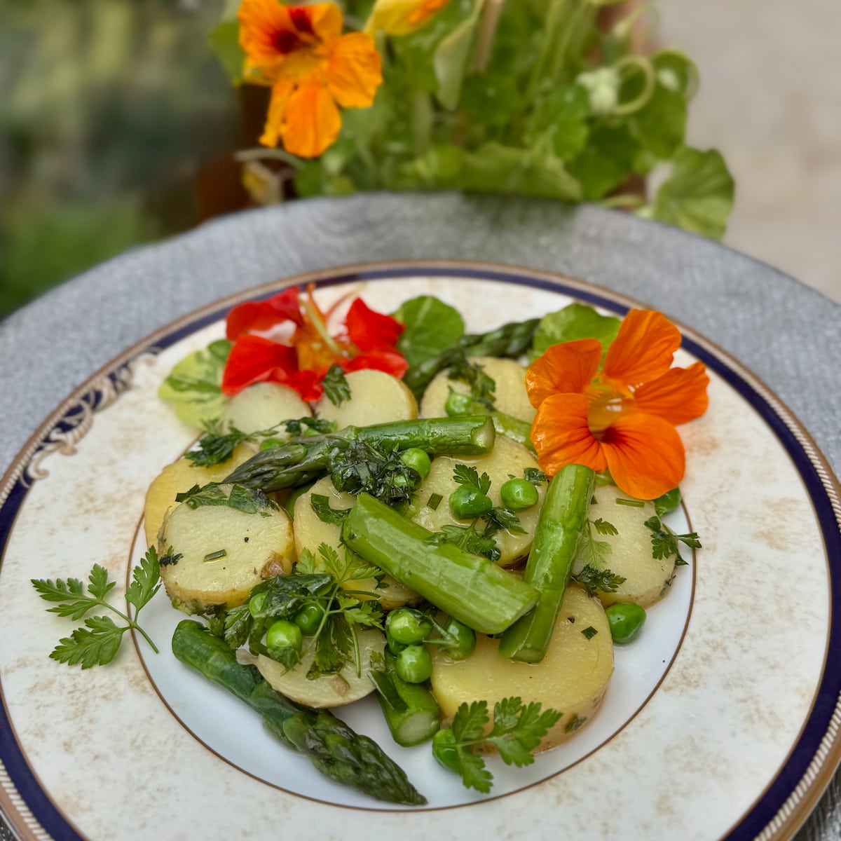 classic French potato salad with added asparagus, peas and nasturtium leaves and flowers