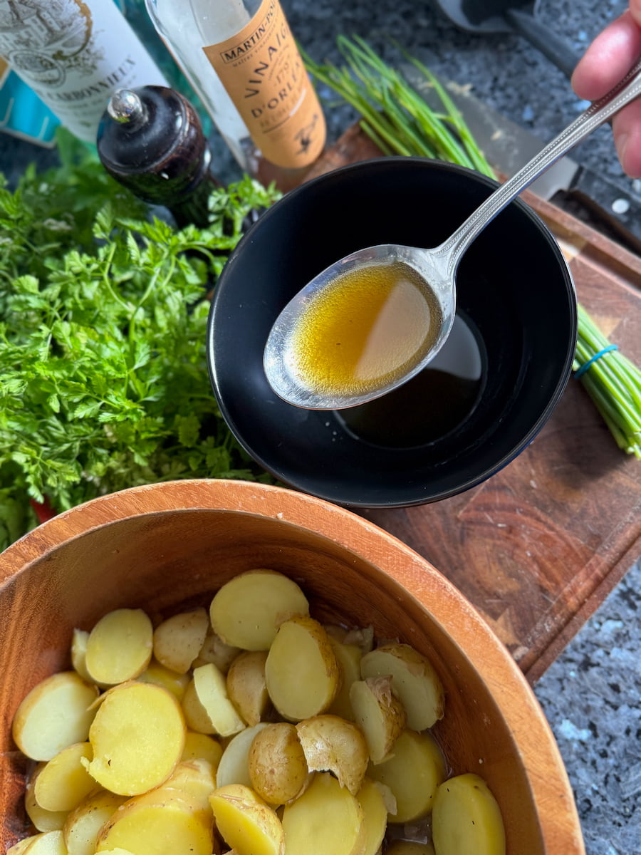 mixing together French cider vinegar from Orleans with olive oil to make a classic vinaigrette for potato salad