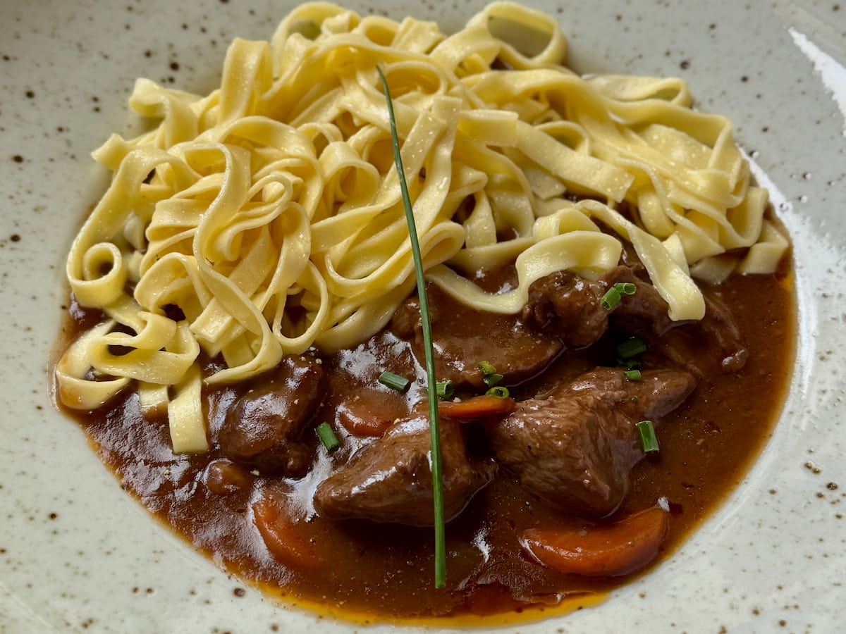 bowl of fresh egg noodles served with a rich beef French stew, Bourguignon